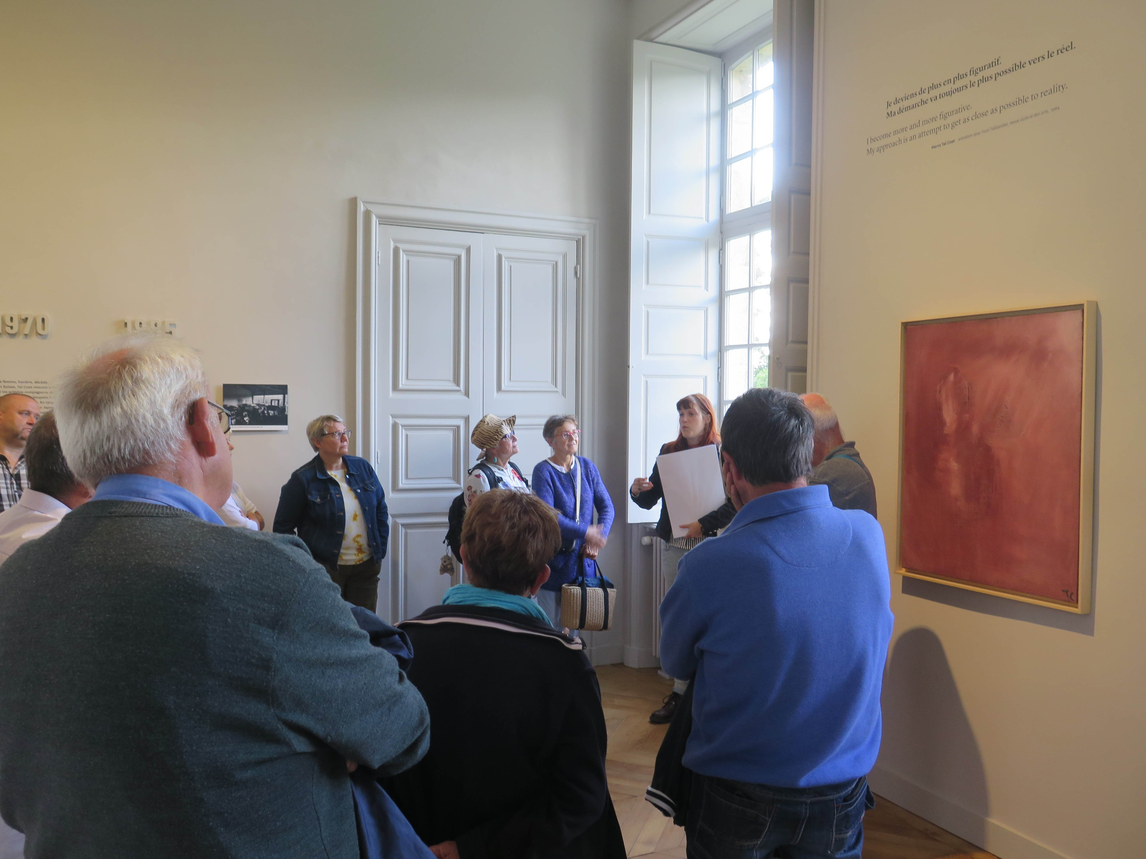 Femme parlant à un groupe dans l'exposition de peintures du peintre Tal Coat.