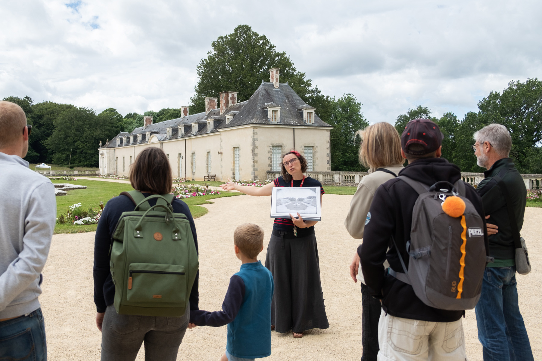 Femme parlant à une groupe dans la cour d'honneur du château.