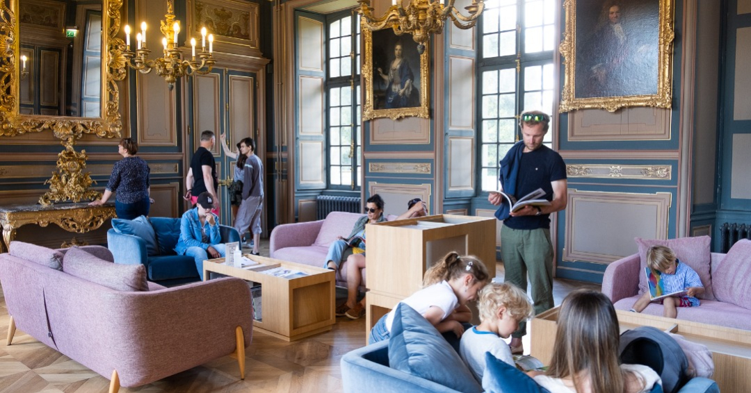 Photo de l'intérieur du chateau, dans un salon avec du public