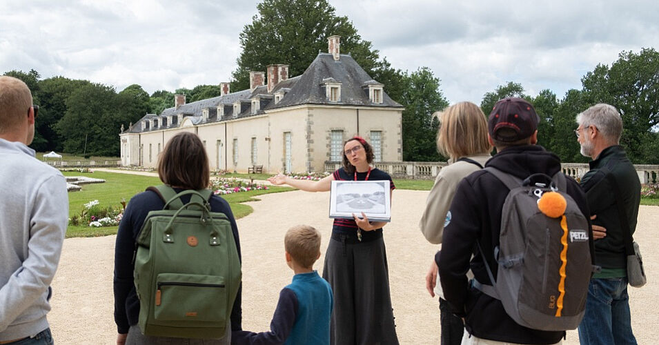 Photo prise dans la cour d'honneur du château, représentant une visite guidée avec une médiatrice et le public autour