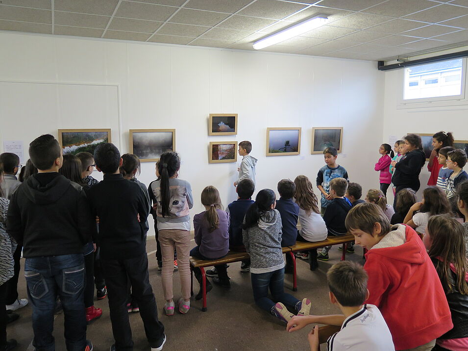 Personnes visitant une exposition de photographies dans une école.