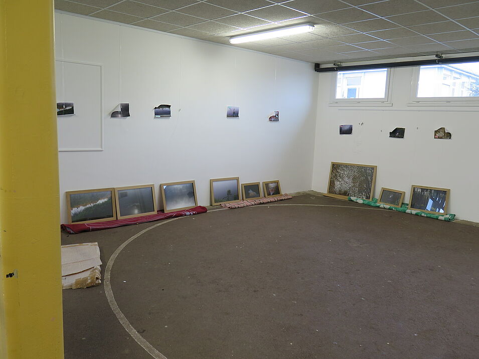 Salle d'une école avec l'accrochage en cours de photographies encadrées.